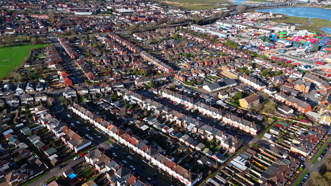 Flugschwenk über den Vorort Totton westlich des Flusses in Southampton, England, mit Autos auf den belebten Straßen und Sonnenlicht, das sich im Winter auf dem blauen Flusswasser mit Booten darauf spiegelt