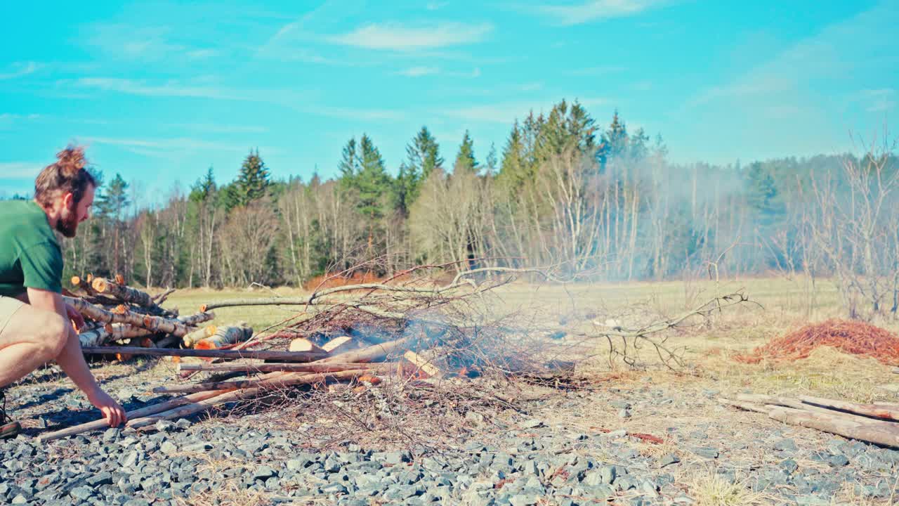 Man Burning Poles Near The Forest - Wide Shot