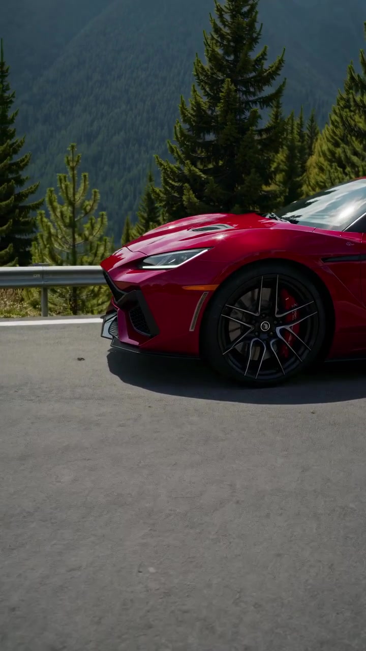 Lussuosa auto sportiva rossa parcheggiata su una strada di montagna panoramica.