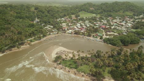 Epische-Luftaufnahme-Von-Fischerbooten,-Die-Im-Hafen-Verankert-Sind,-Während-Der-Atlantik-Auf-Den-Ortiore-fluss-Auf-Der-Insel-Trinidad-Trifft