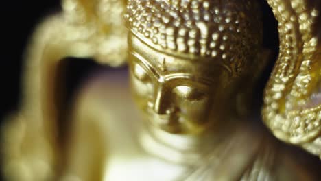 Close-up-shot-of-golden-Buddha-figurine-with-incense-stick-burn-coming-from-side