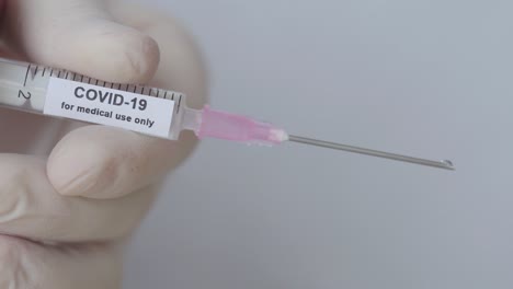 Doctor's-Hand-With-Glove-Pushes-Syringe---COVID-19-Vaccination---close-up