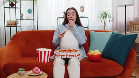pregnant woman eating unhealthy junk fatty fast food pizza popcorn crisp watching movie at home