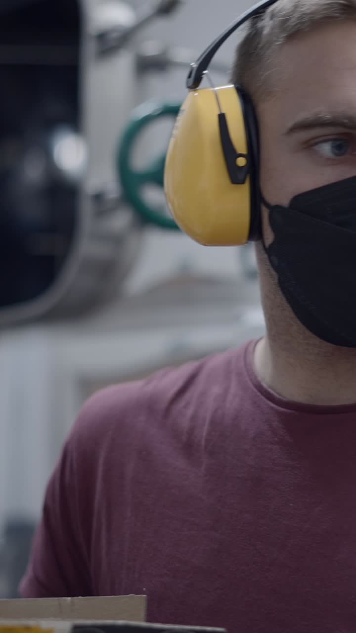 Man Wearing Mask and Earmuffs Working in an Industrial Setting