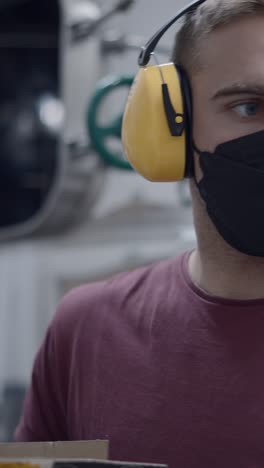 man wearing mask and earmuffs working in an industrial setting