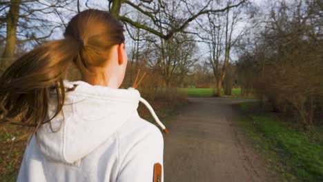 rising follow shot of young woman jogging in the park