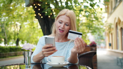 woman using mobile phone to make a payment at a cafe