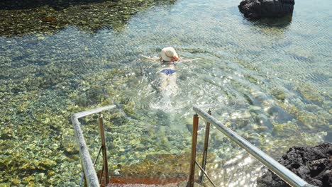 Wunderschöne-Frau-Mit-Hut,-Die-Im-Atlantik-Auf-Teneriffa-Schwimmt,-Rückansicht