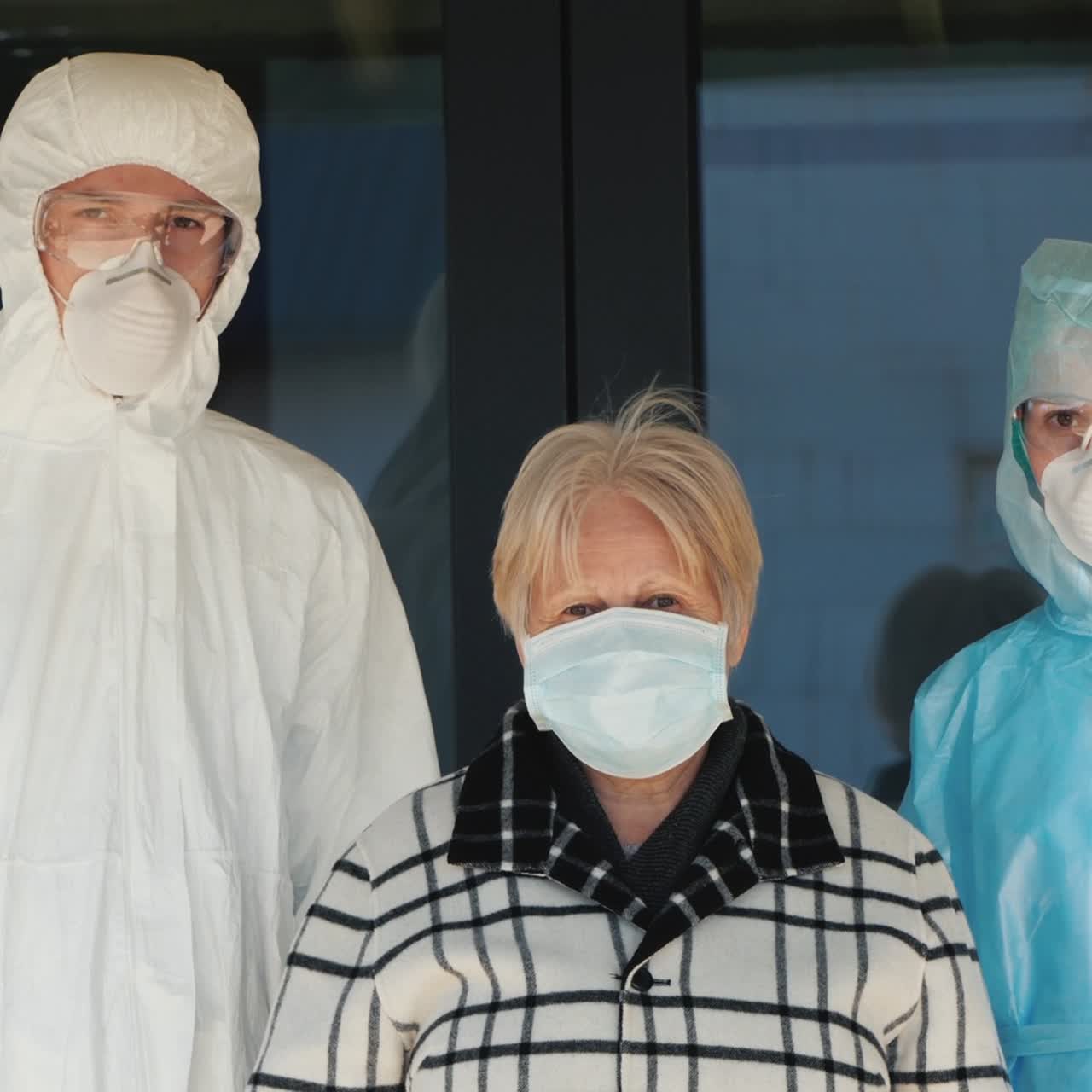 Portrait Of An Elderly Woman With Medics In Protective Suits