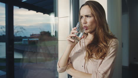 Concentrated-woman-staying-near-panoramic-window.-Pretty-woman-waiting-for-man.