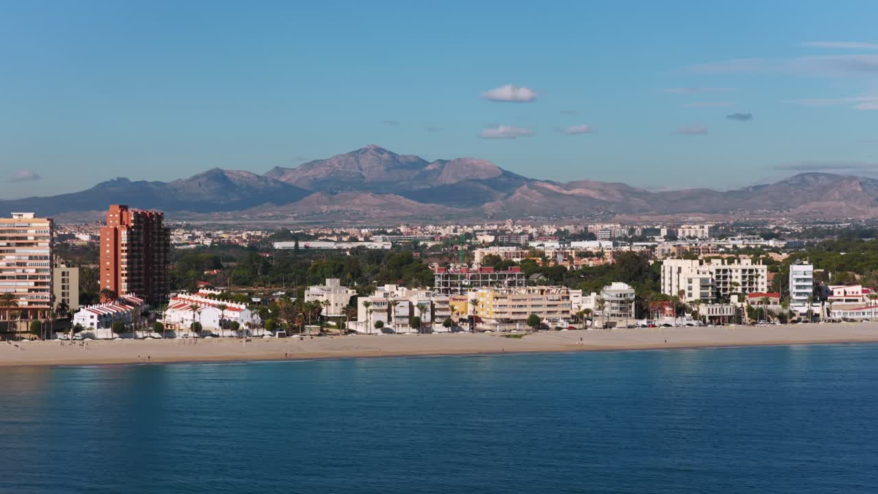 Costa con hotel ed edifici residenziali in una giornata di sole ad Alicante, Spagna. Vista aerea laterale da drone, spazio per il testo