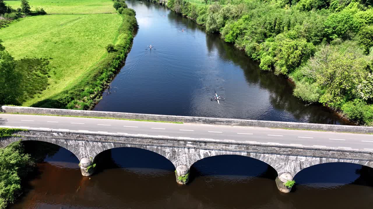 Aerial View of Stone Arch Bridge over River with Rowers