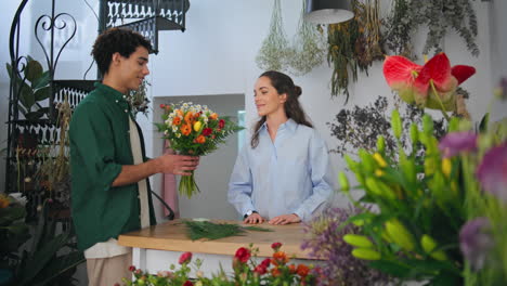 grateful customer shop flowers in plant store. happy worker florist sell bouquet