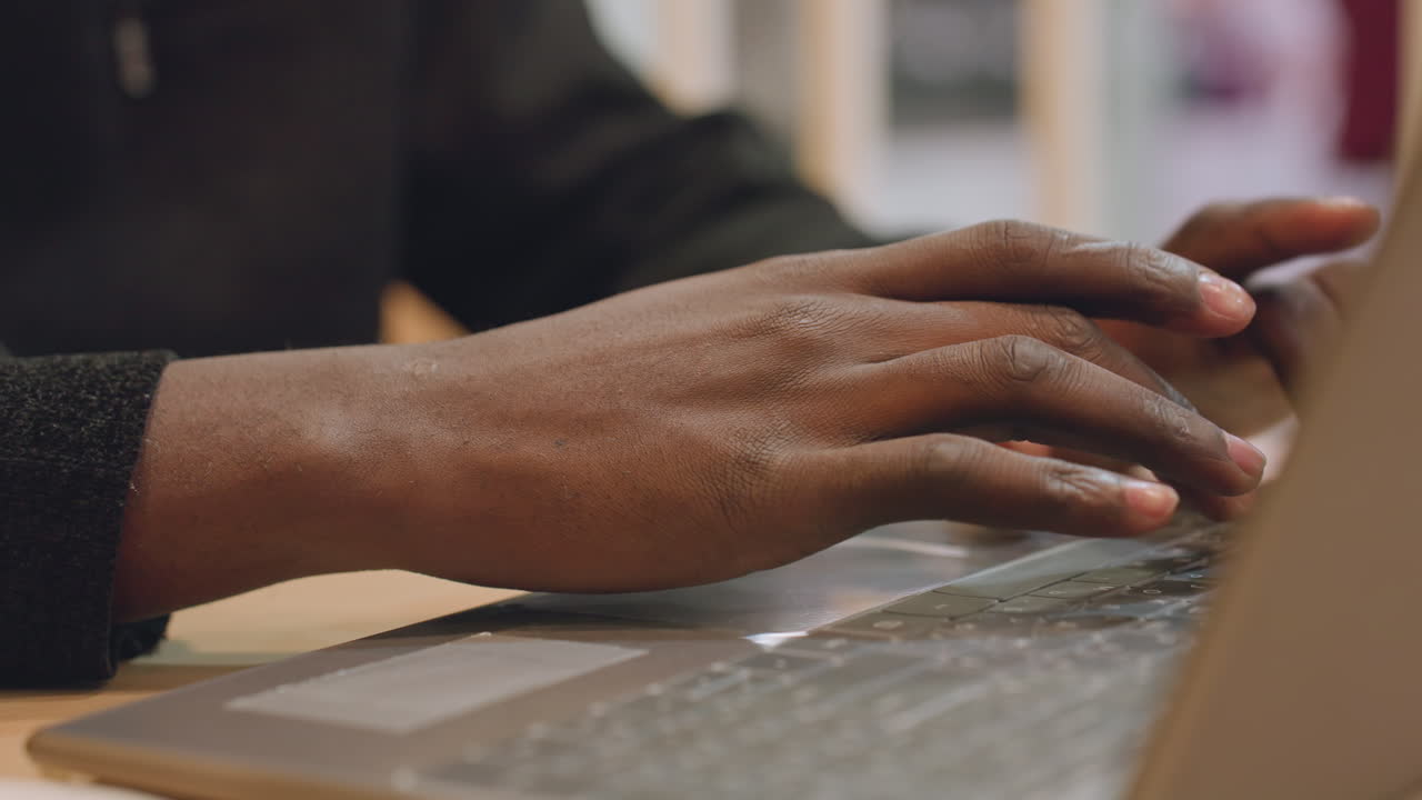 Black hands typing laptop prototype interface, UX designer testing mockup, studio lighting, deliberate gestures on keyboard and trackpad, collaboration notes visible, creative workflow