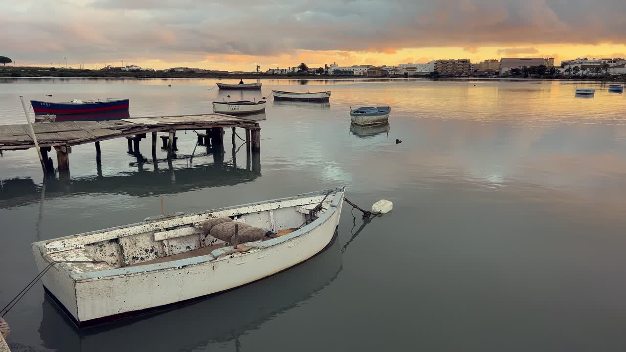pequeños barcos de pesca están flotando suavemente en las aguas tranquilas de barbate, andalucía, durante una pintoresca puesta de sol, creando una atmósfera serena y pacífica