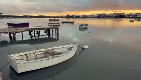 small fishing boats are gently floating on the calm water of barbate, andalusia, during a picturesque sunset, creating a serene and peaceful atmosphere