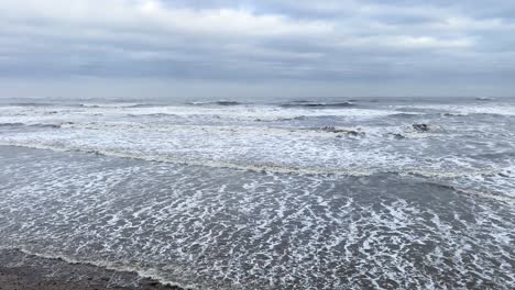 rough waves thrashing on a cold beach from the north sea during a cloudy day