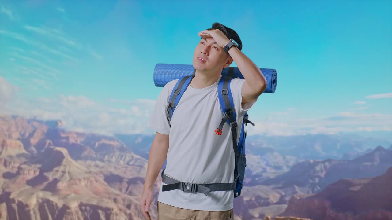 Asian Male Hiker With Mountaineering Backpack Hand Forehead Smiling And Looking Distance While Traveling At The Top Of Mountain