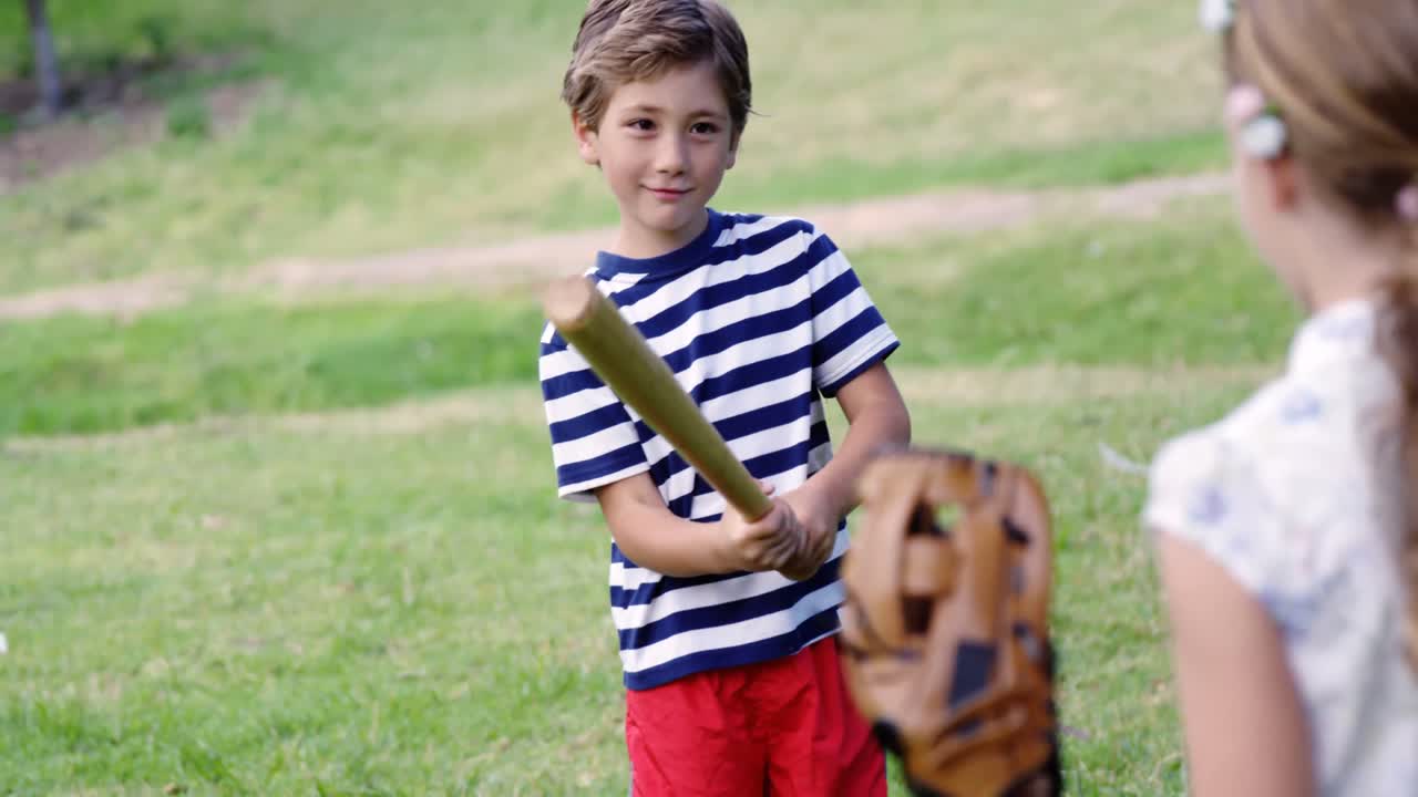 Sisarukset pelaamassa baseballia puistossa