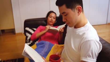 couple relaxing on sofa reading book in living room