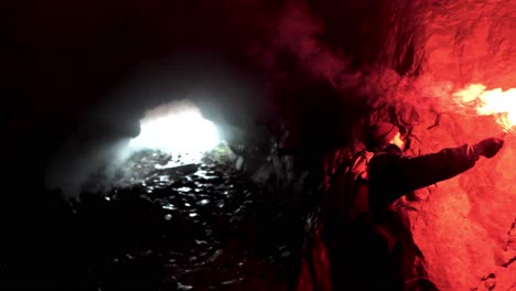 man with red smoke signal in cave