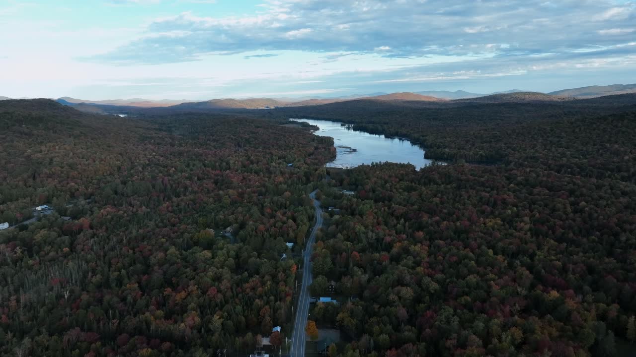 bosque boreal en el follaje de otoño con vista a la carretera y el lago en adirondack, nueva york