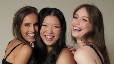 close up of three smiling women standing close and looking towards the camera