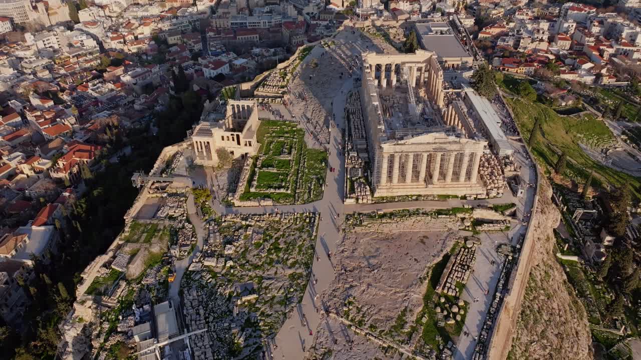 Plano de drone cinematográfico em movimento para trás, revelando a Acrópole e o Partenon em Atenas, Grécia. Ruínas antigas, horizonte histórico e perspectiva dramática criam uma cena poderosa para viagens e cultura