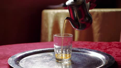 pouring tea from silver teapot in the riad, morocco, slow motion