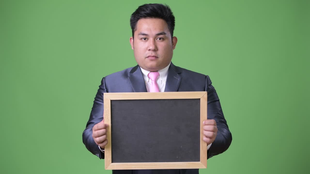 초록색 배경에 젊은 잘생긴 과체중 아시아 사업가