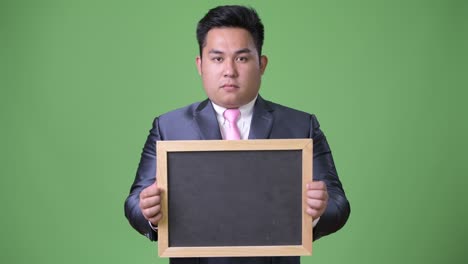 초록색 배경에 젊은 잘생긴 과체중 아시아 사업가