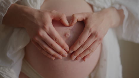 pregnant woman forming heart shape on belly