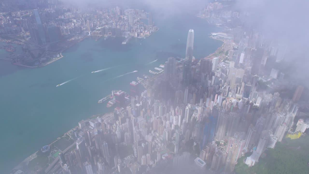 Epic aerial view of the Victoria Harbour in a clear day, with thick cloud and sunlight
