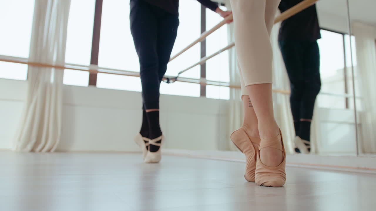 Legs of Two Ballet Dancers Rehearsing at the Barre