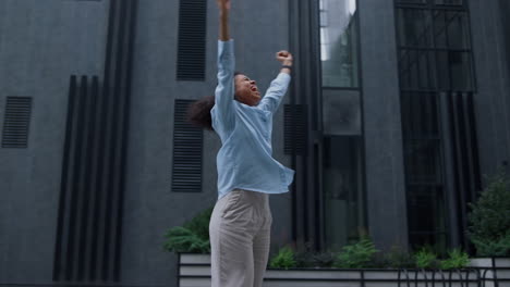 happy woman celebrating victory dancing alone on modern business center yard.