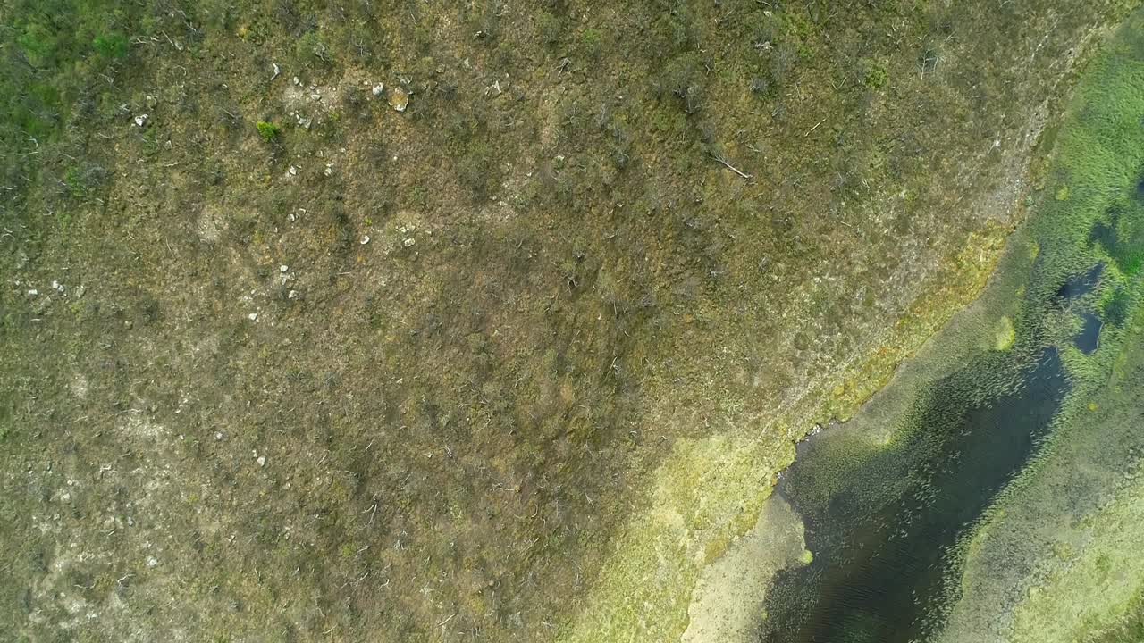 dron volando sobre un verde paisaje montañoso escarpado con lago, río y bosque exuberante.