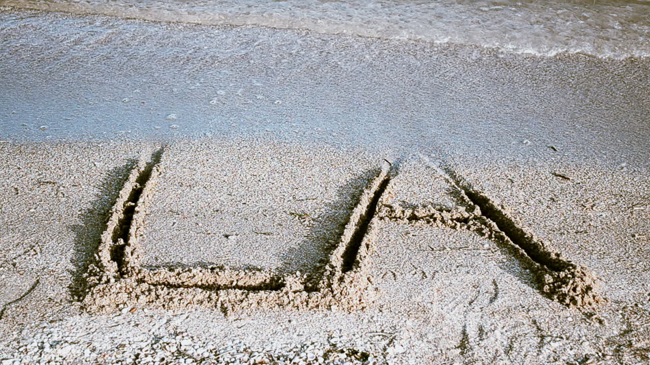 Inskripsjonen LA på sand. Inskripsjon på sand, stranden.