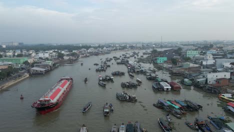 Large-cargo-ship-navigates-Can-Tho-River-among-smaller-boats,-Vietnam