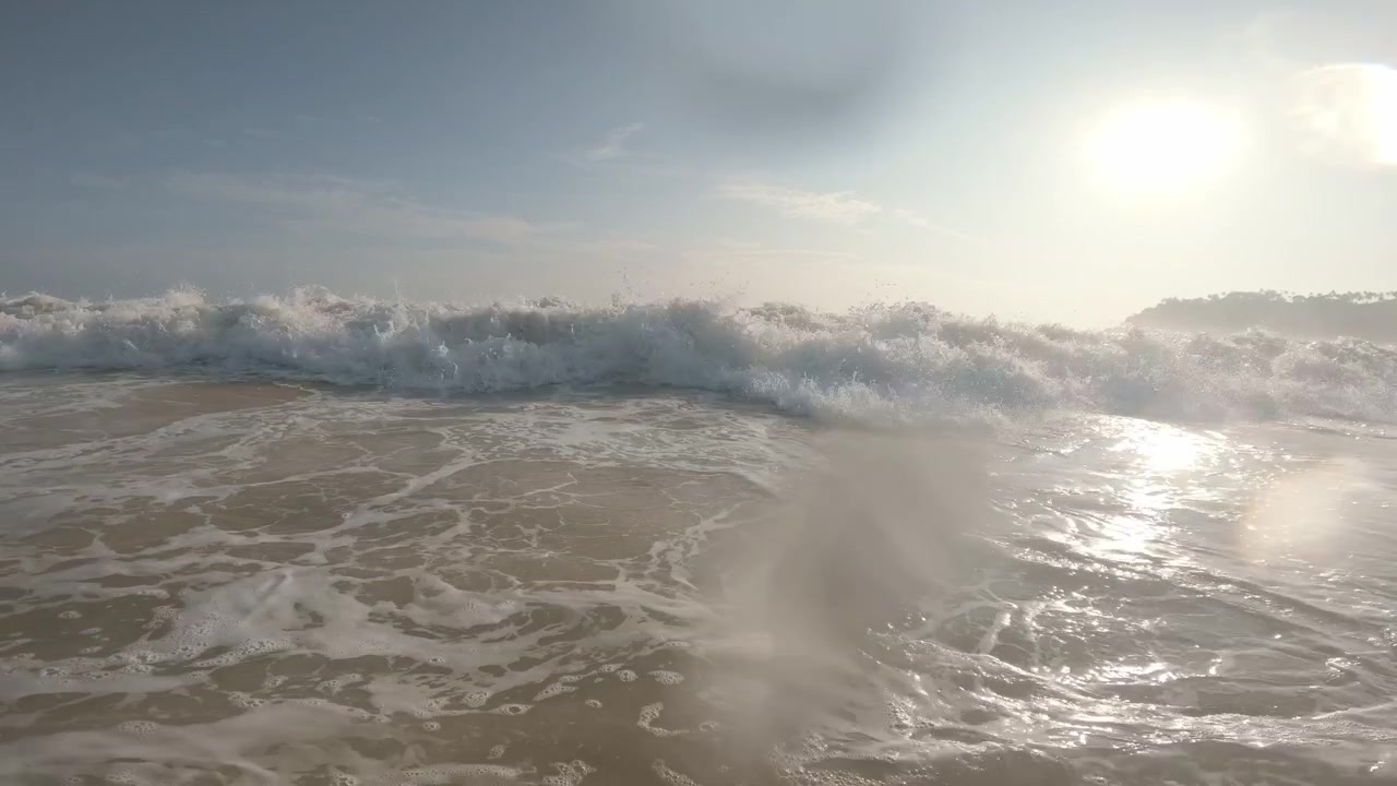 A backlit shorebreak rises through sunlit foam, then surges over a low water-level camera at Mirissa Beach, Sri Lanka, until turbulent whitewater fills the lens.