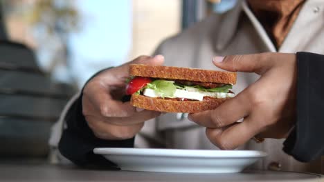 mujer comiendo un delicioso sándwich de feta y verduras