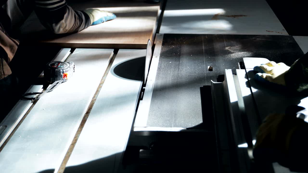 두 명의 알아볼 수 없는 목수나 목수들이 새로운 날카로운 원형 도자기를 사용하여 판을 잘라니다.