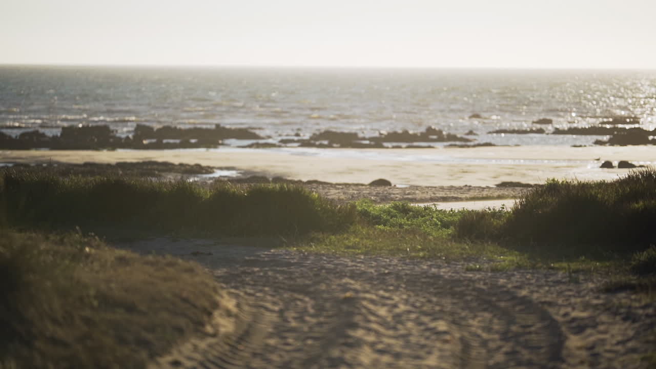 Morning Sunrise Over The Calm Blue Ocean During Summer With Unpaved Road That Leads Down To The Beach. - wide shot