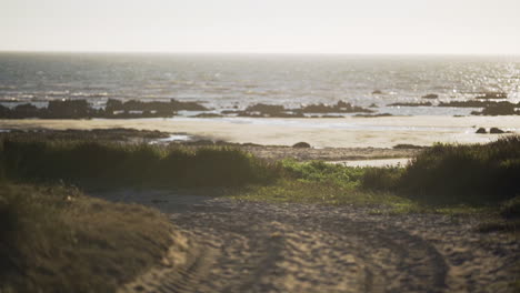 morning sunrise over the calm blue ocean during summer with unpaved road that leads down to the beach. - wide shot