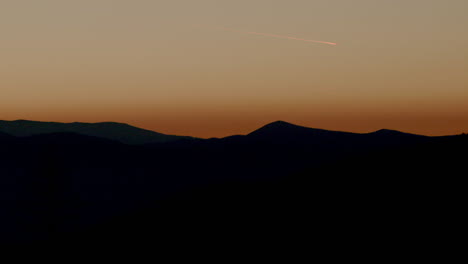 silhouetted mountain horizon with plane flying