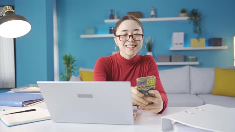 Asiatische-Frau-Schaut-Auf-Ihr-Telefon-Und-Arbeitet-An-Einem-Laptop,-Glücklich-Und-Voller-Energie.