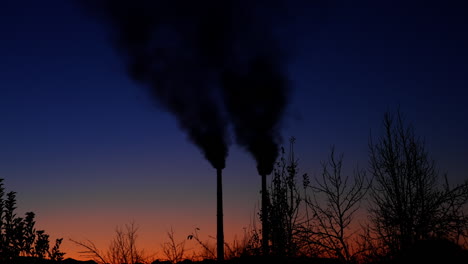 amazing blue and pink sky in the dusk. silhouettes of plant pipes produce smoke emitting it into the air.