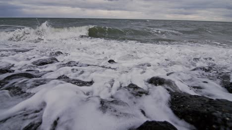 waves crashing over rocks, foam splashing on a beach in domburg, the netherlands, super slow motion