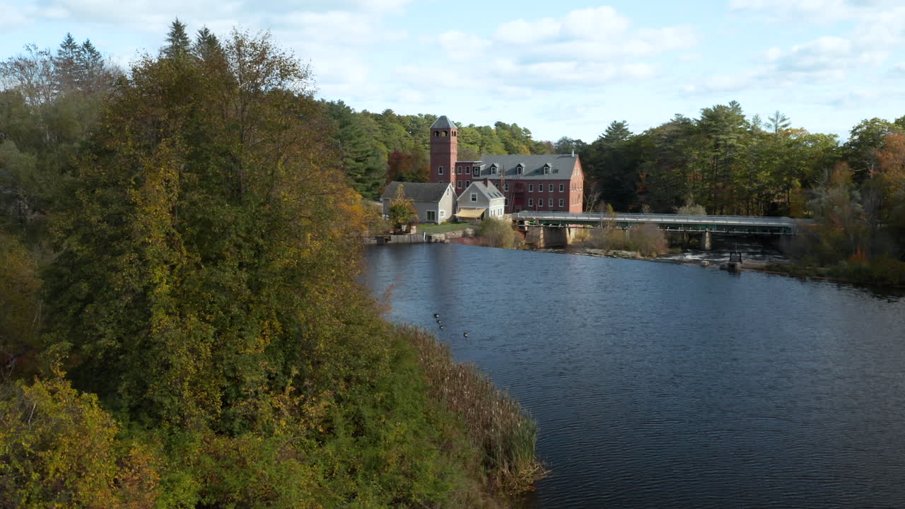 hermosa toma aérea de seguimiento lateral que revela el molino de sparhawk cerca del río real en maine