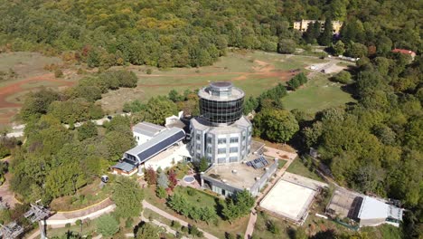 Slow-motion-drone-shot-of-Dajti-mountain-cable-car-office-reveals-Tirana-valley-and-city-landscape,-Albania,-Europe