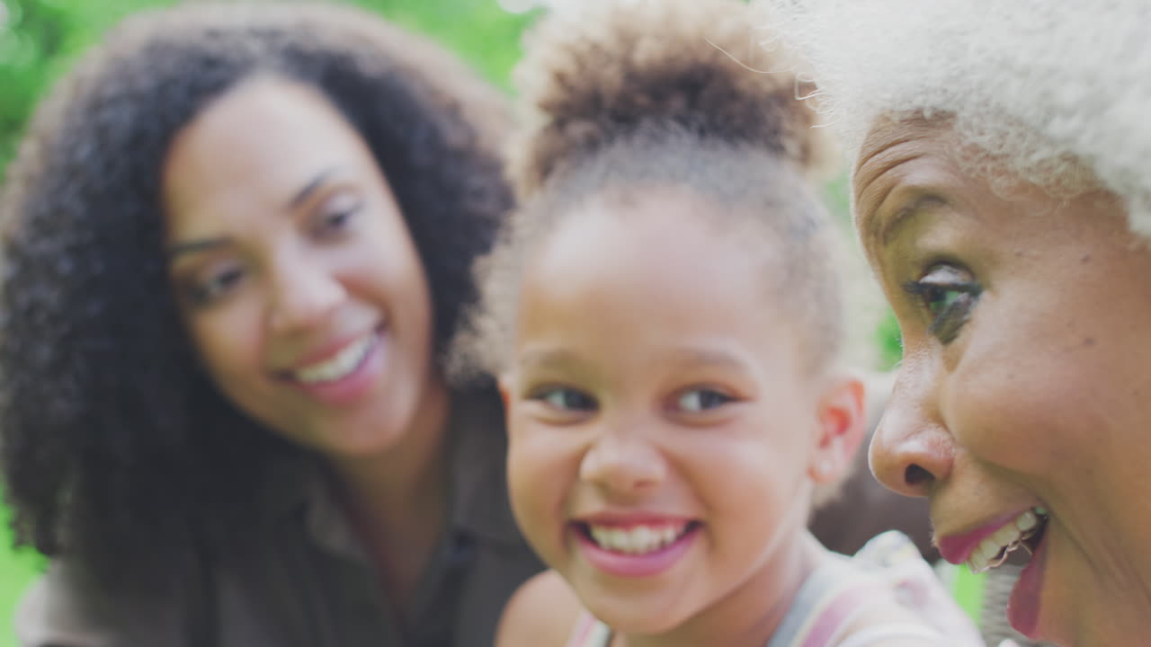 Smilende kvindelig flergenerationsfamilie i haven derhjemme
